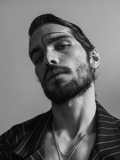 A close-up black and white portrait with graphic line makeup. This editorial shot focuses on creating a mood, with the simple styling of a chain necklace adding a subtle edge.
