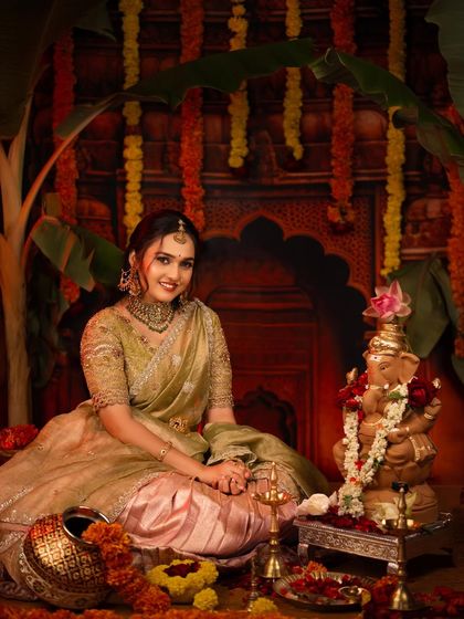 A serene portrait of a young woman sitting beside a Ganesha idol, surrounded by flowers and traditional decorations for the festival.