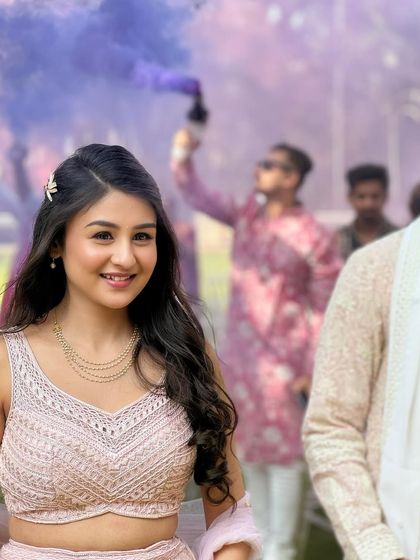 A beautiful shot of the bride with a purple smoke bomb in the background. Her soft, romantic makeup for the Haldi event looks ethereal.