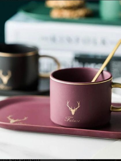 An elegant deer-themed mug and tray set in maroon and gold, a sophisticated gift included in a welcome hamper for a groom.
