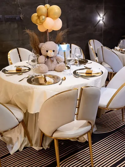 The guest tables at the elegant teddy bear party were beautifully set with gold chargers and a teddy bear centerpiece. The modern chairs with gold accents complemented the sophisticated look.