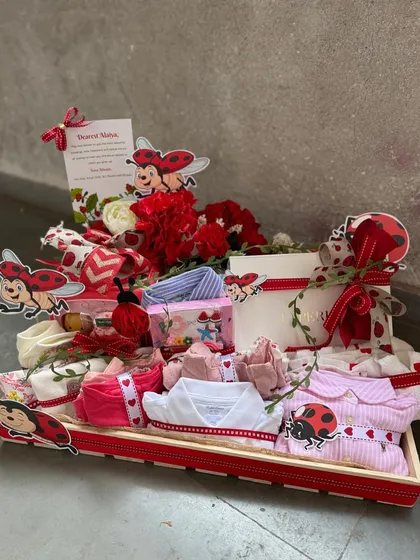 A closer view of our ladybug-themed baby hamper, showcasing the neatly rolled baby clothes, themed ribbons, and a personalized card, ready to be gifted.