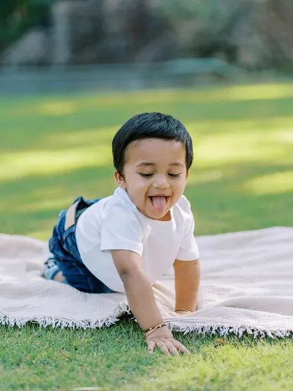 A playful moment of a baby crawling on a blanket outdoors, sticking his tongue out. It's these quirky, real moments that I love to capture.