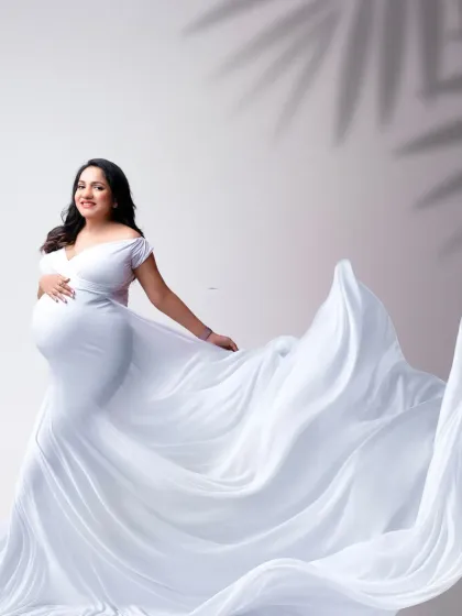 A graceful pose with a sweeping white train. The contrast of the simple gown with the dramatic fabric creates a visually stunning and elegant maternity portrait.