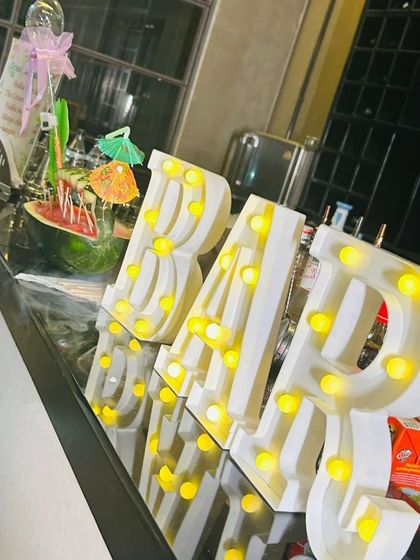 The bar is the heart of the party. We use decorative elements like marquee letters and creative garnishes, like this watermelon drink dispenser, to make the bar a focal point.