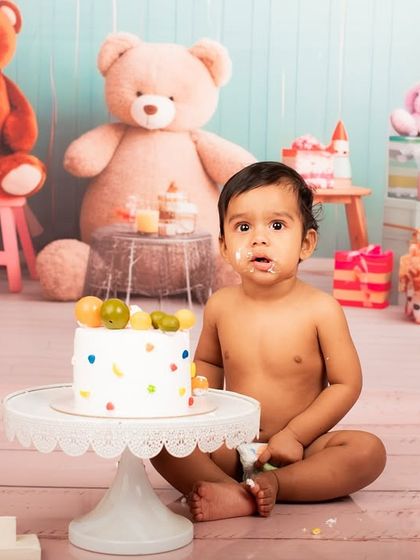 A little bit of cake on the face makes for the cutest photos. This baby is enjoying his cake smash session, surrounded by a playful teddy bear theme.