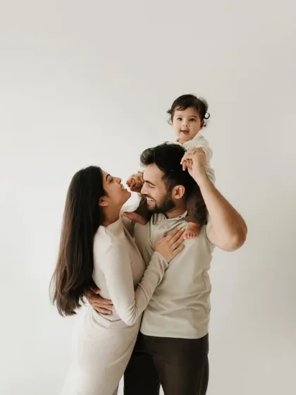 A classic family pose with the baby on dad's shoulders. The parents' loving gaze at each other makes this a beautiful family portrait.