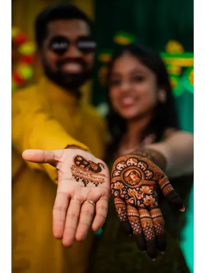 The couple proudly displays their mehendi. The bride has a portrait design, while the groom has a fun, simpler design.