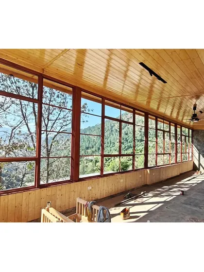 An interior view from a boutique homestay we designed in the Kumaon Hills of Uttarakhand. The expansive windows and warm wood paneling are designed to frame the majestic landscape, creating a seamless connection between the indoor space and the natural world outside.