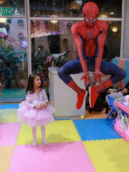 The moment a princess meets a superhero. This photo captures the surprise and delight as Spider-Man makes a dynamic entrance at a princess-themed party, showing how we can mix themes for a unique celebration.