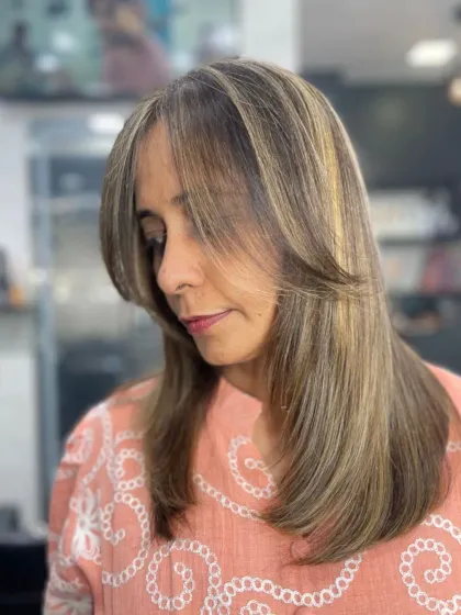 A soft, layered cut with curtain bangs and subtle highlights, framing the face beautifully.