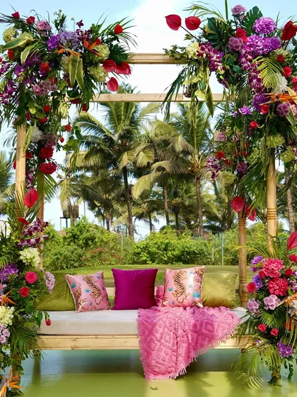 A beautiful swing seat for the bride, framed with lush tropical flowers and greenery, set against the palm trees of Goa.