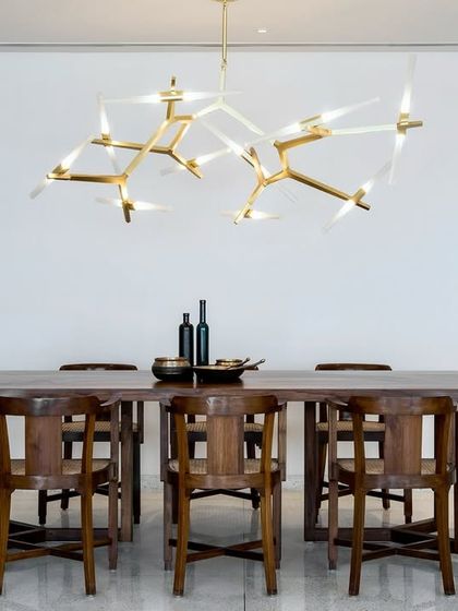 The dining area in the Terrazzo Residence is anchored by a striking modern chandelier. We kept the surrounding decor minimal to draw attention to the custom wooden dining set and the clean, white space.