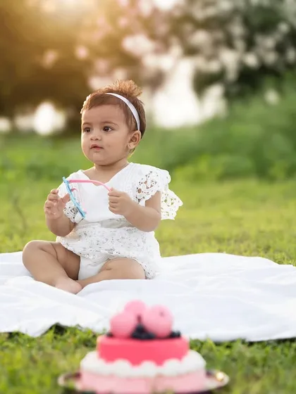 A serene outdoor cake smash session at sunset. The golden light adds a warm, magical glow to this special first birthday memory.