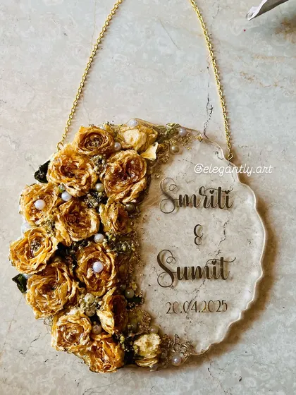 This beautiful wall-hanging frame preserves a varmala in a half-moon design. The preserved yellow roses are complemented by the couple's names and wedding date on the clear resin side.