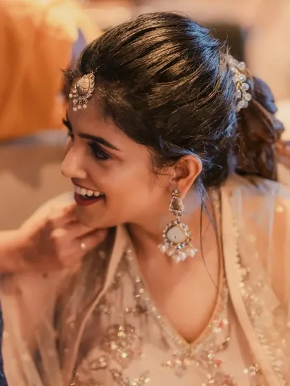 A close-up of the bride's happy expression. The soft glam makeup enhances her features, with a focus on a flawless base and a touch of shimmer on the eyes.