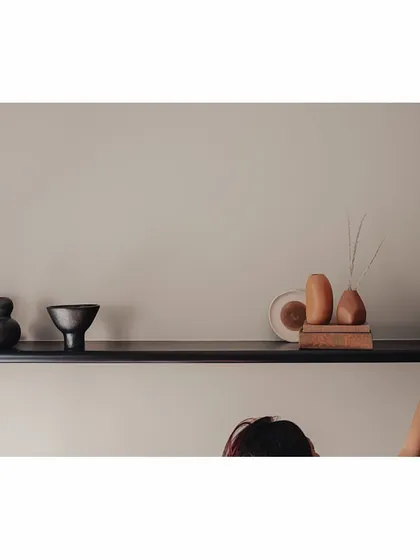 A sleek, black burnt-wood shelf is filled with curios from around the world. This guest bedroom is designed to be a place to reminisce and laze, and these personal objects, carefully arranged, add to the room's story and character.