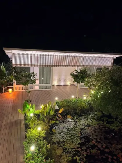 Warm lighting on the deck and in the garden creates a cozy and inviting atmosphere around the lily pond at night. This design allows the homeowners to enjoy their waterside landscape long after the sun has set.
