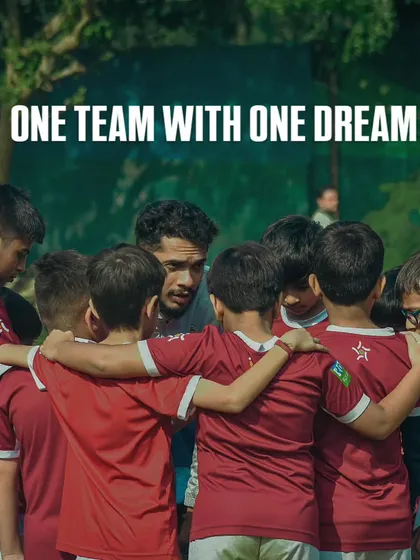 One team, one dream. We foster a culture of unity and collective ambition. Here, our coach and players huddle up, focused on a shared goal before a big game.