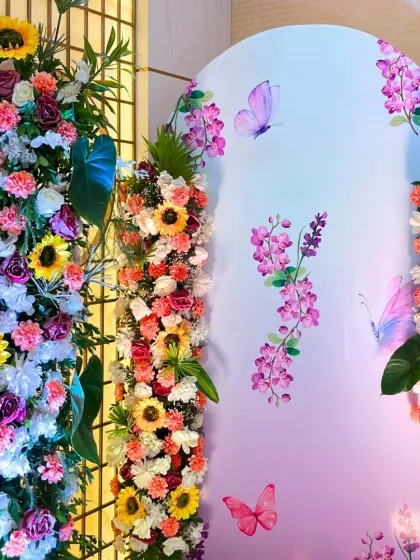 A close-up of the vibrant floral arrangements, showing the rich mix of sunflowers, roses, and carnations against a pastel backdrop with butterfly decals.