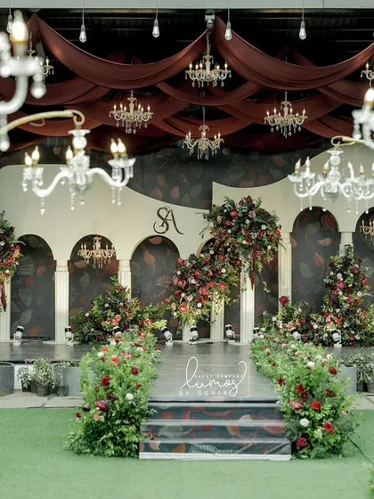 A vision of royal romance, this reception stage combines deep red draping, crystal chandeliers, and lush floral arrangements. It’s a design that speaks of timeless elegance and grandeur.