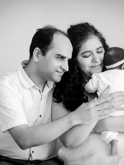 A tender moment between new parents and their baby, captured in classic black and white.