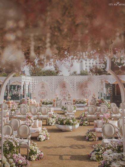A dreamy, soft-focus view of the wedding aisle. The path is lined with lush flowers, leading towards the intricately designed stage, creating a truly romantic journey for the bride.