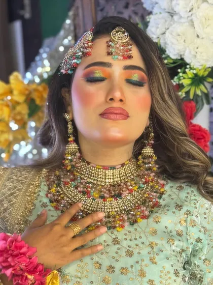A beautiful shot of the Haldi bride with her eyes closed, showing off the vibrant and artistic eye makeup in full detail.