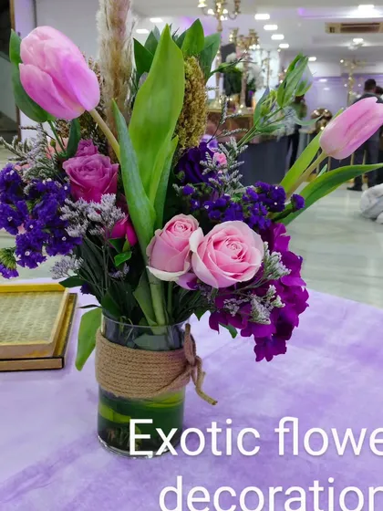 A charming and rustic vase arrangement. This bouquet of pink tulips, roses, and purple filler flowers is perfect as a centerpiece for a small table or as a decorative accent.