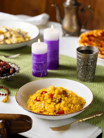 A bowl of risotto from the Ramadan menu at The Big Chill Cafe UAE. The scene is styled with candles and dates to evoke an Iftar meal.