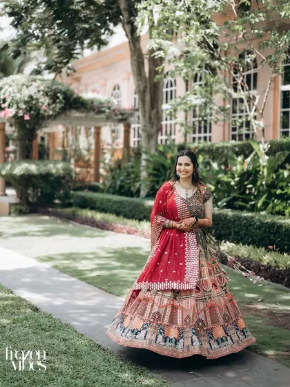 A beautiful solo portrait of the bride, Shubhi, walking through the resort gardens. Her colorful lehenga looks stunning against the green background.