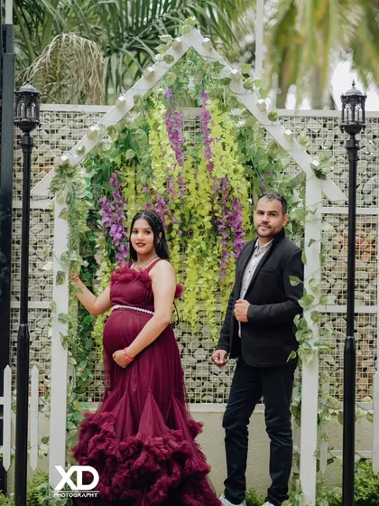 A lovely couple's portrait framed by a white garden arch decorated with flowers, creating a romantic and whimsical feel.