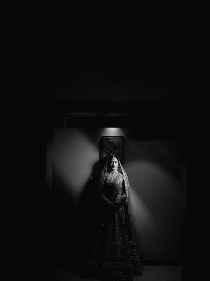 A powerful black and white bridal portrait using dramatic lighting. The single light source creates a spotlight effect, resulting in a moody, artistic, and unforgettable image.