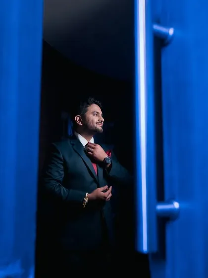 Suit up! A creative shot of the groom adjusting his tie, framed by a bold blue doorway.