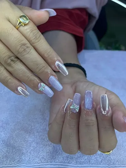 A beautiful set of long, coffin-shaped nails with a pearlescent finish and delicate silver bow charms.