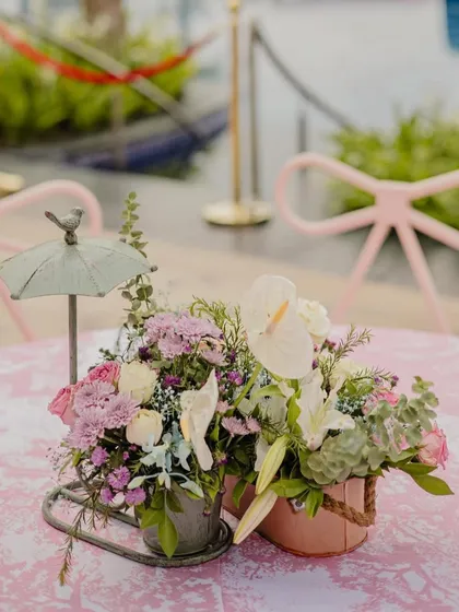 A charming floral centerpiece with a miniature umbrella, adding a whimsical touch to the pastel-themed decor.