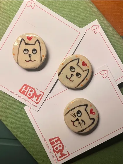 Sometimes I trade my needle and thread for clay. These quirky cat badges are hand-built and painted ceramic pieces, each with its own funny little expression. They are a fun alternative to my embroidered work for all the cat lovers out there.