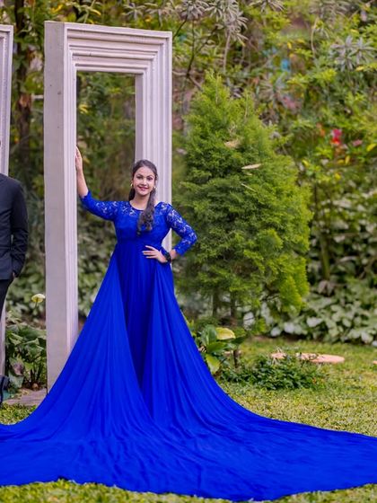 A couple poses with our unique oversized white photo frames set amidst the lush green lawn and trees, perfect for a creative outdoor shoot.