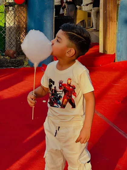 A superhero in training enjoying a super-sized bite of our fluffy cotton candy at an Avenger-themed birthday bash.