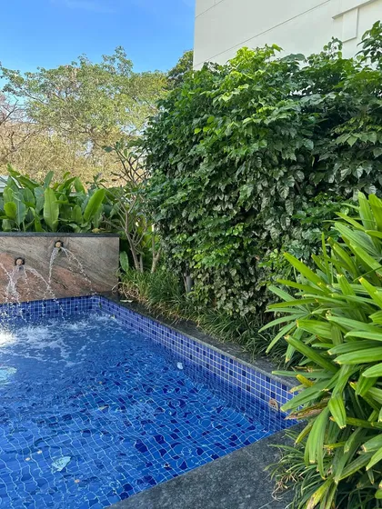 I designed this apartment's poolside area to feel like a private, tropical retreat. The dense foliage and water feature create a serene environment for residents to relax and unwind.
