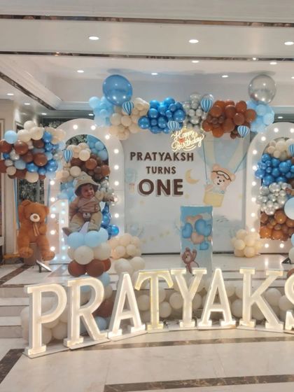 The main stage for the teddy bear party, with lighted arches, a custom backdrop, and large marquee letters spelling out the birthday boy's name.