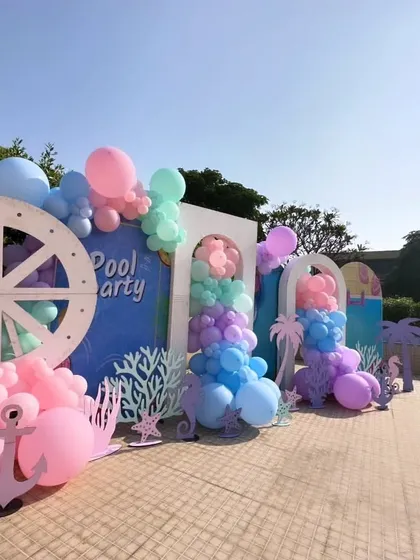 This shot showcases the full photo backdrop area for the pre-wedding party. The setup includes multiple arches, a variety of themed props, and carefully placed balloon arrangements to create a dynamic and fun space for pictures.