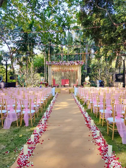 A picturesque view of the aisle leading to the outdoor mandap, lined with rose petals and candles, creating a romantic pathway for the bride's entrance.