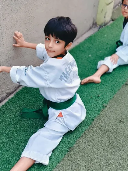 This young student works on his split against the wall, showing great determination. This foundational stretch is practiced in every class to build flexibility over time.