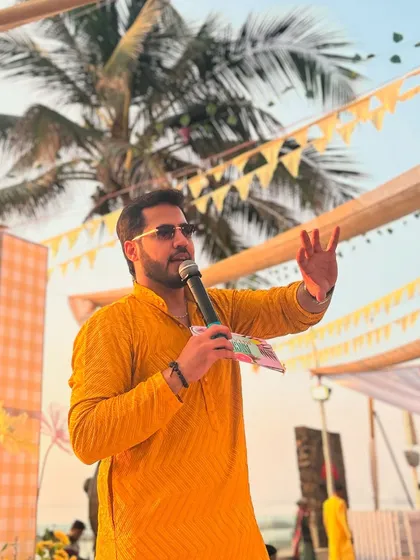 Mic in hand, addressing the guests at a beautiful outdoor Haldi. I'm always ready to engage and entertain.