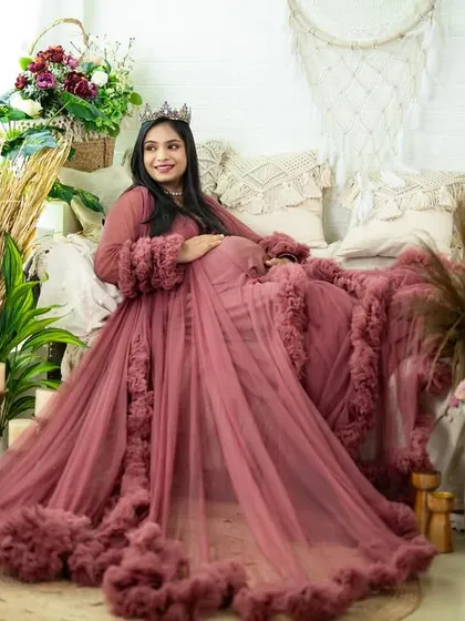 This dusty rose gown with ruffled trim offers a soft, romantic feel. The mom-to-be is surrounded by our boho studio props, creating a rich and textured portrait full of warmth.