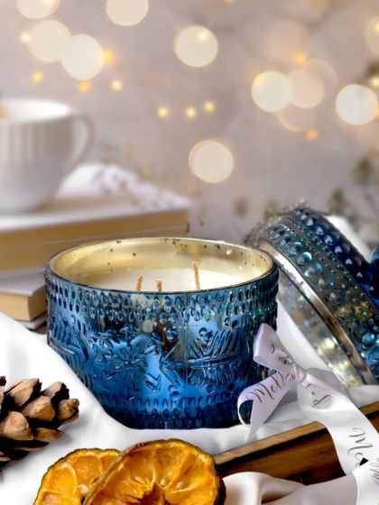 An open view of the blue candle jar, revealing the gently lit wicks inside. The composition, with its festive props and soft lighting, invites you to experience a moment of winter serenity.