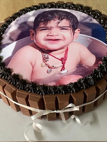 A personalized photo cake is a wonderful way to celebrate a loved one. Here, I've placed an edible photo on a delicious chocolate cake, surrounded by a border of KitKat bars and rich chocolate frosting for a sweet and personal touch.