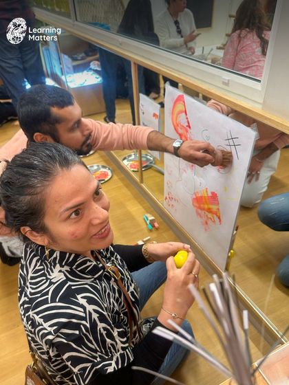 A parent gets creative during our orientation, painting on a large vertical surface. We invite parents to experience our learning environment firsthand to see how we encourage joyful exploration and self-expression.