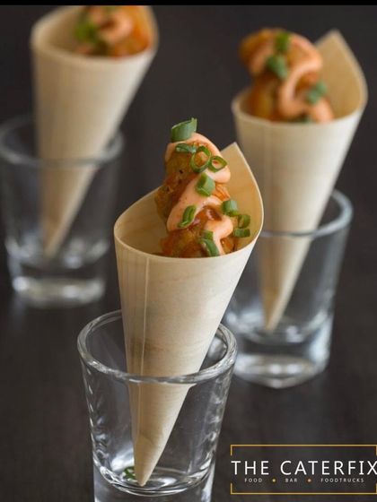 These are crispy fried vegetable balls served in paper cones with a drizzle of spicy mayo. This presentation makes them easy for guests to enjoy while socializing at cocktail parties or corporate events.